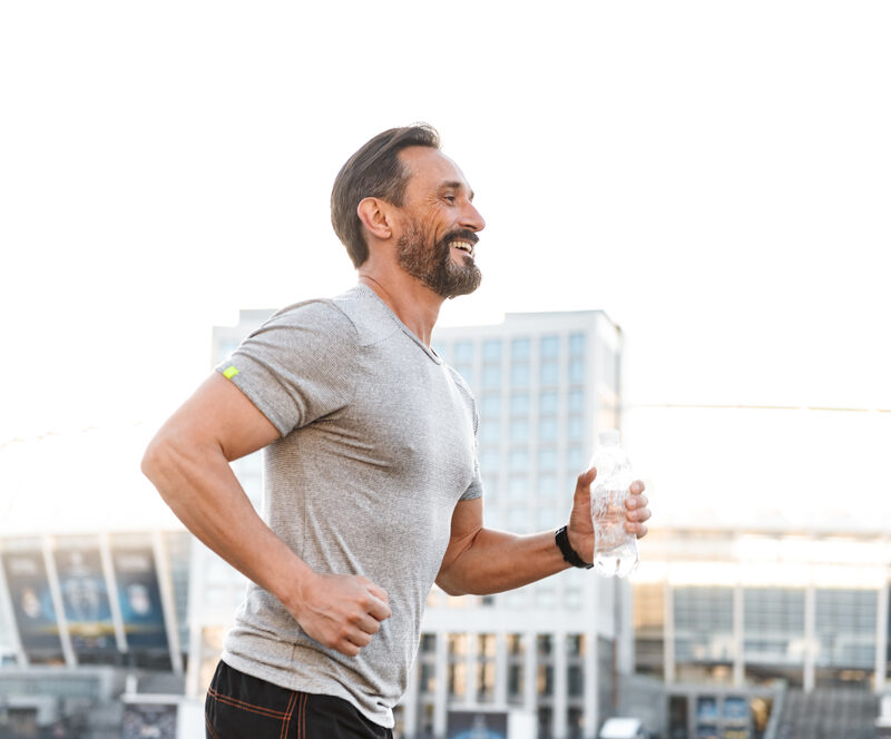 Man jogging outdoors while holding a water bottle