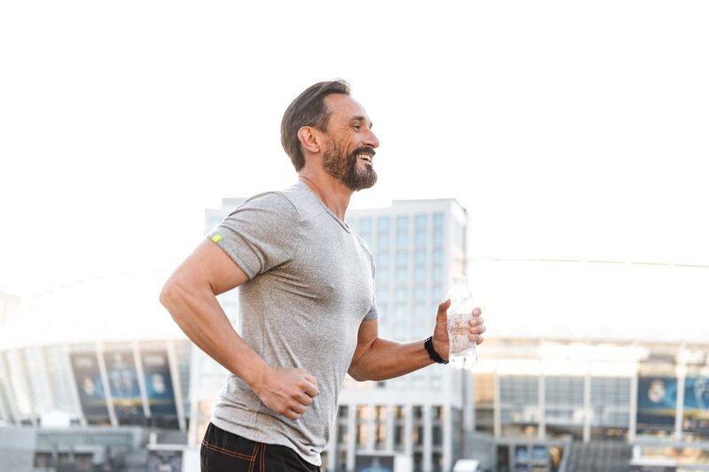Man jogging outdoors while holding a water bottle
